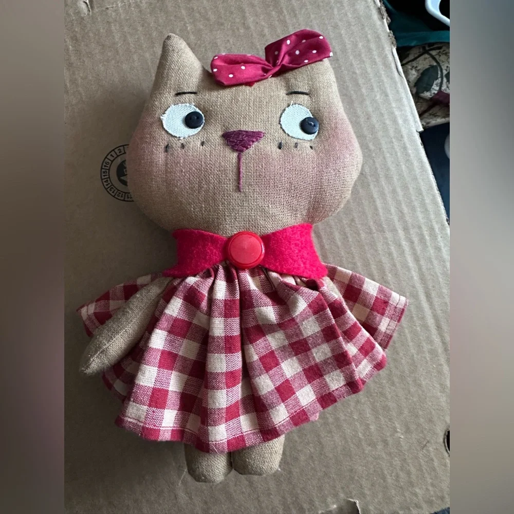 Handmade cloth cat doll in a red and white plaid dress.